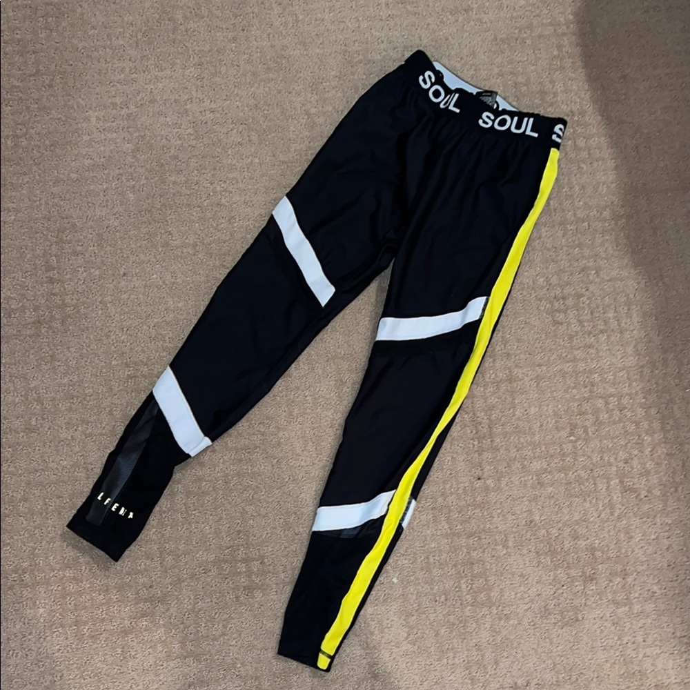 ALLFENIX + SoulCycle Black and Yellow leggings with mesh.